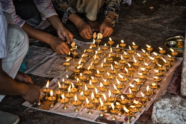 மக்கள் தரையில் வெண்ணெய் விளக்குகளை ஒளிரச் செய்கிறார்கள். பிரார்த்தனைக்காக உள்ளூர் செய்தித்தாள் ஆவணங்களில் நடைபாதையில் விளக்குகள் ஊற்றப்படுகின்றன. நேபாளம், ஆசியா — ஸ்டாக் புகைப்படம்