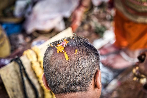 Närbild av ett huvud med kort hår och gula blomblad på kronan för bön. Asien. Hinduism — Stockfoto