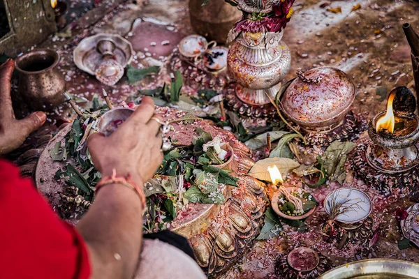 Pequeño santuario en el suelo para oraciones inductivas con pétalos de flores y gadgets de oración y ofrendas con la mano de un feligrés rezando. Nepal. Países Bajos . —  Fotos de Stock