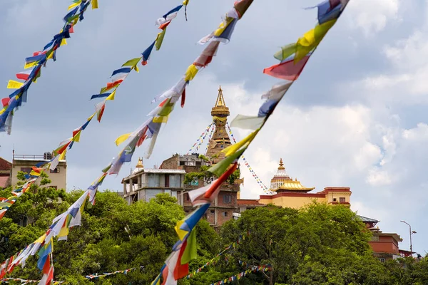 ネパール・カトマンズの青空が広がる夏の日に、風に揺れるチベットの色鮮やかな旗を持つヒンドゥ教寺院の眺め — ストック写真