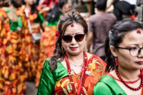 Ağustos 2019 'daki Raksha Bandhan Yatra partisini kutlamak için kırmızı ve güneş gözlüğü takmış Hindu kadınlar sırada, Patan. Nepal.