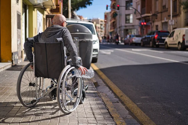 Wheelchair disabled person picking up a transparent plastic bottle thrown and abandoned on the floor to throw it into the garbage recycling container and avoid being contaminated. Avoid plastics — Stock Photo, Image