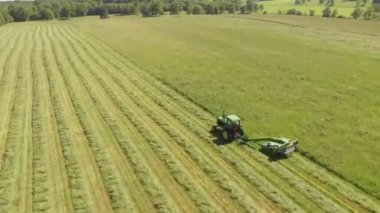 Traktör büyük bir arazide çim kesiyor.
