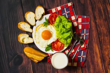 Ekmek, kızarmış yumurta, süt ve sebze ve ahşap arka plan üzerinde kızarmış domates adet ile Kahvaltı