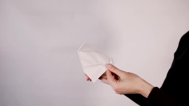 Die Atemschutzmaske in den Händen in Großaufnahme auf weißem Hintergrund — Stockvideo