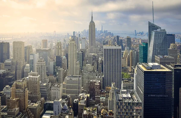 Iconic aerial view of New York City on a sunny day. Sunbeams between the skyscrapers, and cloudy background. Concept of travel. NYC, USA — Stock Photo, Image