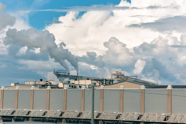 Concept of pollution. The smoke from the chimneys, mixes with the clouds in a blue sky. Canada.