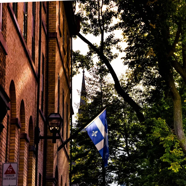 Quebec flag on a red brick building in the sunset light. Canada.