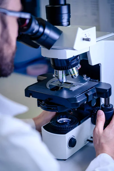 Scientific handling a light microscope examines a laboratory sample for pharmaceutical bioscience research. Concept of science, laboratory and study of diseases.