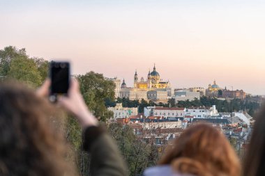 Tanınmayan turistler fotoğraf çekiyor ve Almudena ile Kraliyet Sarayı 'nın manzarasının tadını çıkarıyor. Madrid, İspanya. Seyahat konsepti ve teknoloji.