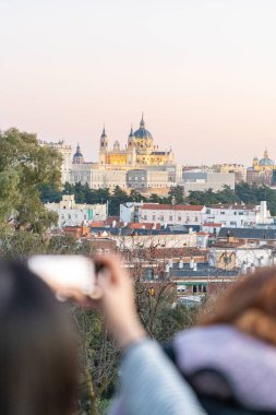 Tanınmayan turistler fotoğraf çekiyor ve Almudena ile Kraliyet Sarayı 'nın manzarasının tadını çıkarıyor. Madrid, İspanya. Seyahat konsepti ve teknoloji.