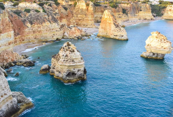 Viewpoint of the natural arches, orange cliffs and turquoise waters, at sunset. Concept of tourism and travel. Algarve, Portugal