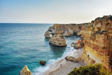 Marinha Sahili 'nin yukarıdan görünüşü. Sadece bir çift kumda yürür. Turuncu kayalıklar ve turkuaz sular. Gürültüsüz turizm ve seyahat kavramı. Algarve, Portekiz