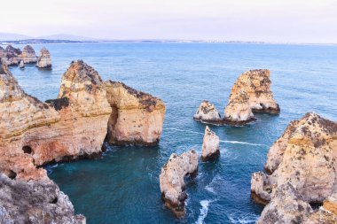 Turuncu renkli kayalıklar ve Truqeussian suları uçurumları. Arka planda Lagos şehri var. Turizm ve seyahat kavramı. Algarve, Portekiz
