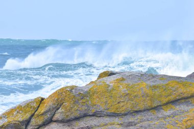 Dalgalar engebeli denizlerdeki kayalara çarpar. Bulutlu bir günde. Galiçya İspanya.