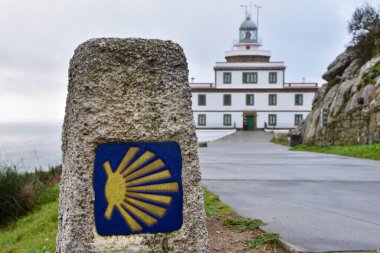 Arka planda Camino de Santiago ve Finisterre Deniz Feneri işareti var. Gün ışığında, bulutlu bir gökyüzünde. Galiçya, İspanya. Galiçya, İspanya