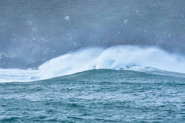 Big waves hit the rocks in rough seas. On a cloudy day. Galicia Spain.