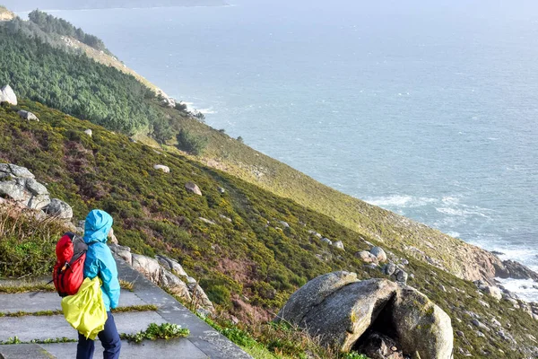 Camino de Santiago yolcusu Finisterre, Galiçya, İspanya 'da ölüm sahili üzerinde denize bakıyor.