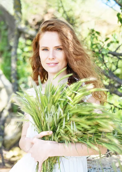 Yeşil dikenli buketli beyaz elbiseli genç kadın.