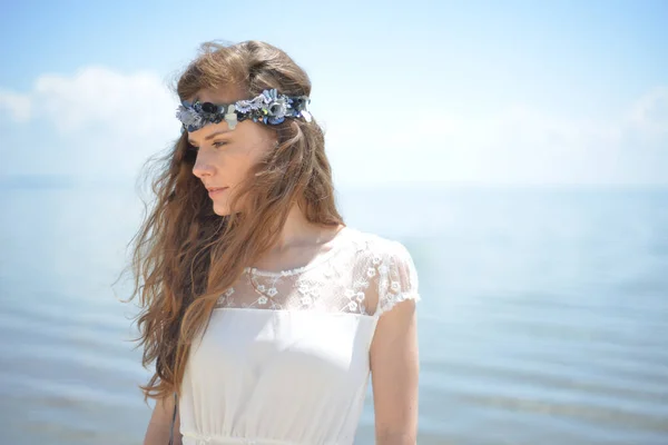 Kafasında aksesuar olan beyaz elbiseli genç kadın.