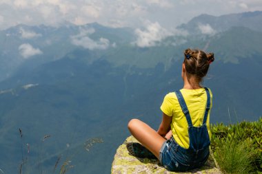 Dağların tepesinde genç bir kız güzel ve manzaralı bir manzaraya karşı.