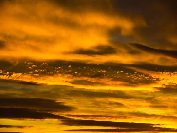 Драматическое золотое небо с освещенными облаками в вечернее время заката — стоковое фото