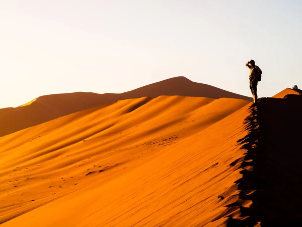 Silhouet van een jonge man die op de bergkam van de Rode duinen in de Sossusvlei, Namib woestijn, Namibië, Afrika — Stockfoto