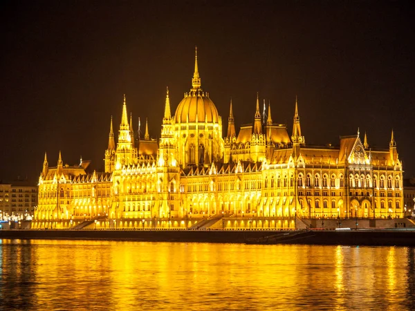 Edificio histórico iluminado del Parlamento húngaro en el banquillo del río Danubio en Budapest por la noche — Foto de Stock