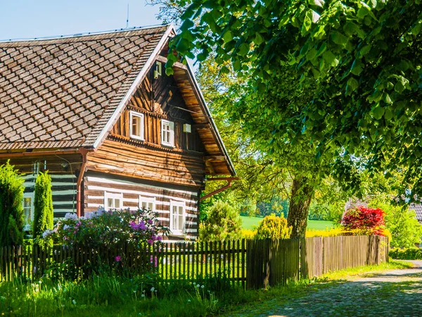 Oude traditionele houten huisje met romantische en idyllische weelderige groene bloementuin met houten hek op een zonnige zomerdag. Tsjechische landelijke architectuur — Stockfoto