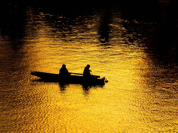船与 2 男子的河里钓鱼。反射的夕阳的天空背景上的黑色剪影 — 图库照片