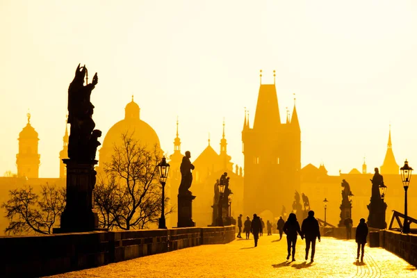 Mlhavé ráno na Karlově mostě, Praha, Česká republika. Východ slunce s siluety lidí, sochy a Staroměstské věže. Romantické cestování destinaci — Stock fotografie