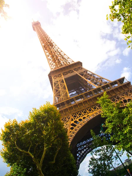 Vista inferior da Torre Eiffel no dia ensolarado de verão, Paris, França. Efeito de fuga solar — Fotografia de Stock