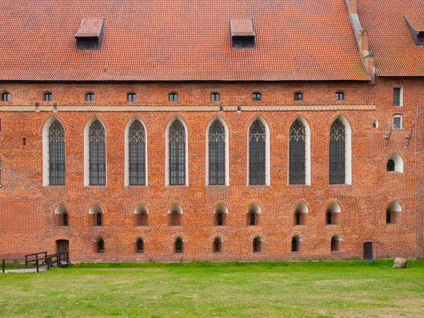 Cihlová zeď s vysokými okny gotické kaple hradu Malbork, Polsko — Stock fotografie