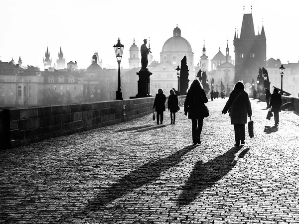 Mistige ochtend op Charles Bridge, Prague, Tsjechië. Zonsopgang met silhouetten van mensen, standbeelden en torens van de oude binnenstad wandelen. Romantische reizen destionation — Stockfoto