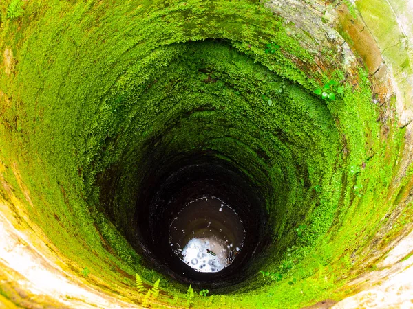 Profondo bene con acqua e muschio verde sulla parete — Foto Stock