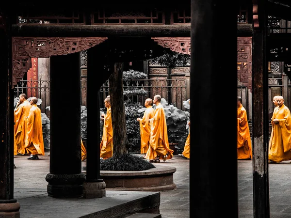 Chengdu, Čína - 27. srpna 2012: Buddhističtí mniši v oranžových procházky mezi sloupci Wenshu kláštera v Chengdu, Čína — Stock fotografie