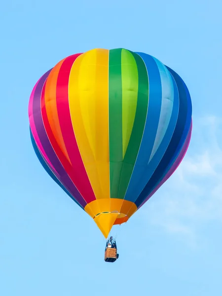 Αερόστατο ζεστού αέρα στα χρώματα του ουράνιου τόξου φάσματος σε φόντο μπλε του ουρανού — Φωτογραφία Αρχείου