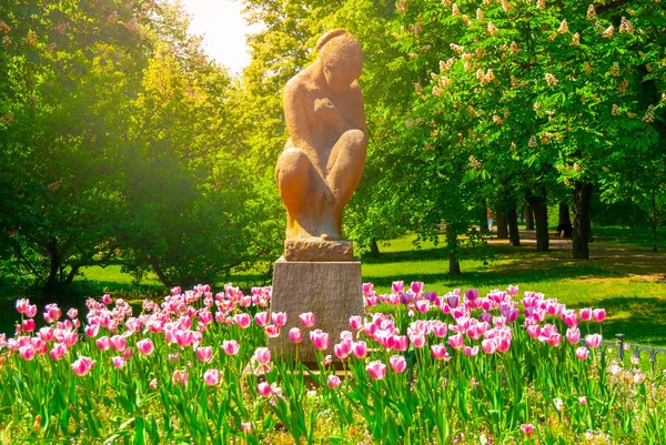 Beeldje van een zittende vrouw in Letná Park op zonnige zomerdag met roze tulpen, Prague, Tsjechië — Stockfoto