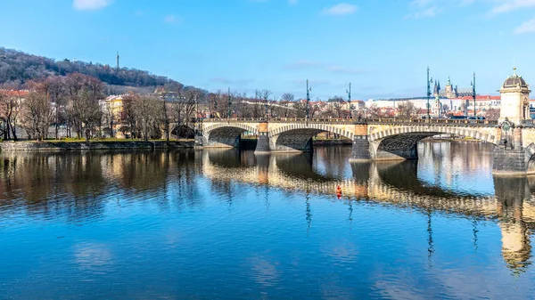Puente de la Legión, Checo: La mayoría legii, reflejado en el río Moldava con el castillo de Praga y Petrin Hill en el fondo. Día de invierno claro y soleado en Praga, República Checa — Foto de Stock