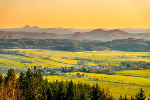 Tepe manzarası gün batımında aydınlandı. Ufukta yeşil çim tarlaları ve tepeler var. Parlak ilkbahar kırsal kırsal, Çek Cumhuriyeti — Stok fotoğraf