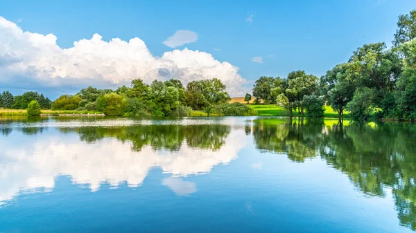 Rural summer landscape reflected in the pond. Blue sky, white clouds and lush green trees — Stock Photo, Image