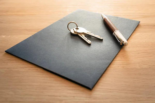 Keys, pen and envelope on the wooden table. Selling or rental of flat, house or another real estate or object. Symbol of agreement Stock Image