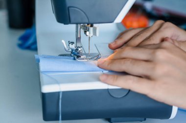 Terzi, terzilik işine başlamak üzere kumaş ve iplikle elektrikli dikiş makinesini kapatır..