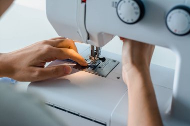 Terzi, terzilik işine başlamak üzere kumaş ve iplikle elektrikli dikiş makinesini kapatır..