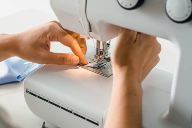 Terzi, terzilik işine başlamak üzere kumaş ve iplikle elektrikli dikiş makinesini kapatır..