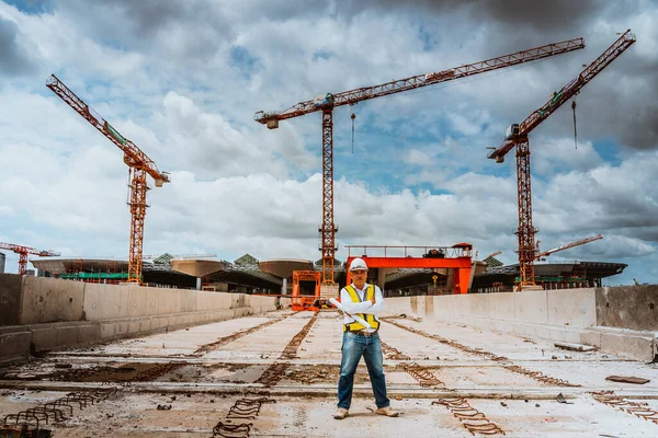 A senior engineer under inspection and checking construction process railway and checking work on railroad station platform .Engineer wearing safety uniform and safety helmet in work.