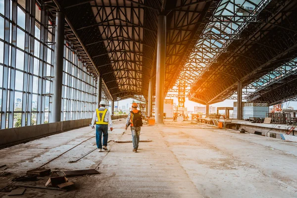 A senior engineer under inspection and checking construction process railway and checking work on railroad station platform .Engineer wearing safety uniform and safety helmet in work.