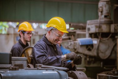 Güvenlik üniforması giyen Endüstri Mühendisliği, endüstri fabrikasında çalışan nesne kontrol işletim makinesini ölçmek için Vernier kalibresini kullandı..