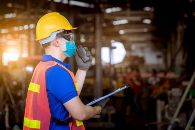 Fabrikadaki kirliliği ve virüsü korumak için güvenlik maskesi takarak fabrika istasyonunda inceleme ve üretim sürecini kontrol eden bir portre işçisi..
