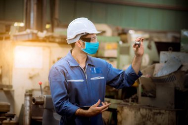 Fabrikadaki kirliliği ve virüsü korumak için güvenlik maskesi takarak fabrika istasyonunda inceleme ve üretim sürecini kontrol eden bir portre işçisi..